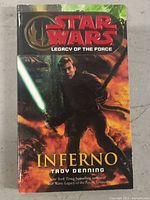 Front cover of Star Wars Legacy of the Force: Inferno book showing character holding a green lightsaber and fire background.