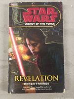 Front cover of Star Wars Legacy of the Force: Revelation by Karen Traviss showing character with red lightsaber and explosion background.