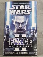 Front cover of Star Wars The Force II Unleashed novel showing character with lightsabers and title.