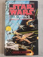 Front cover of Star Wars X-Wing Rogue Squadron book showing space battle artwork with starfighters and star destroyers.