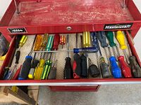 Top view showing assortment of 18 screwdrivers with various handle colors and materials inside a red Mastercraft toolbox drawer.