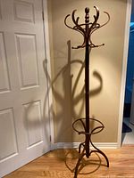 Full view of the tall wooden coat rack showing 10 upper hooks and finial top.