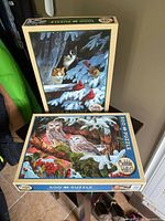 Two Cobble Hill jigsaw puzzle boxes, one standing with cats and cardinals image, the other lying flat showing a bird-themed puzzle.