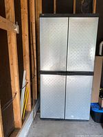 Front view of closed tall garage storage cabinet with silver diamond plate textured doors and black trim, showing overall design and color