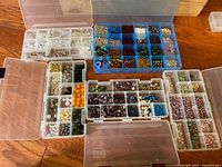 Five compartmentalized organizer cases filled with a wide assortment of beads in multiple colors and materials.