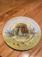 Full front view of the plate showing the central Rococo couple image and gradient yellow and gray border with gold rim.