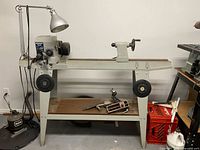 Full side view of Mastercraft wood lathe with tools and lamp on shelf beneath lathe.