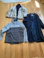 Photo of three men's jackets and coats laid on floor: beige Chaps Ralph Lauren jacket, grey rain jacket with hood, navy blue overcoat.