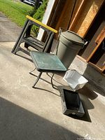 Overview photo showing all items in the lot including sawhorse, trash can, chair, and bins, displayed on concrete flooring near garage entrance.