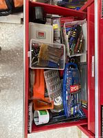 Top view of toolbox drawer showing organized and loose drill and screwdriver bits, hole saws, tap and die box, and wire brush