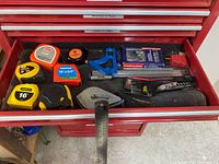 Drawer with 6 tape measures, utility knife, combination square, hand levels, ruler, tool bit set and chalk line reel