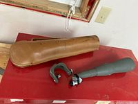 Monolux M-2 spot scope with leather carrying case on red surface, showing size and accessories