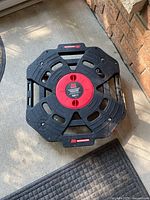 Top view of Motomaster platform tire dolly showing black plastic surface with red circular center label.