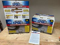 Two unopened boxed Rust-Oleum EpoxyShield garage floor coating kits on a wooden table with instructions sheet visible.