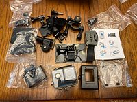 Salpido 4K Ultra HD action camera with waterproof housing along with multiple black mounts, straps, brackets, charger and instruction manual laid out on a wooden surface.