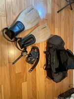 Photo showing the entire snorkeling set including fins, mask, snorkel, dive watch, and carrying bag placed on wood floor.