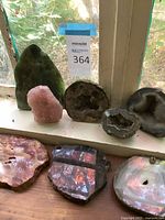Green polished stone arch, rose quartz chunk, geode halves and agate slices on windowsill