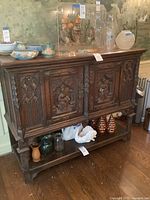 Front view of cabinet showing carved panels and lower shelf