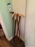 Four canes leaning against wall showing full shafts and varied handles