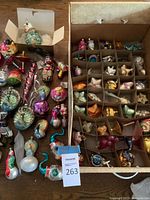 Table display of loose and boxed glass ornaments showing variety of shapes and colors
