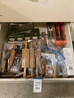 Open drawer with assorted kitchen baking tools including wooden rolling pins with carved patterns, various molds, and boxed Match-O-Matic cookie press
