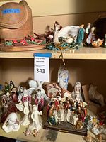 Shelving with assorted figurines including Last Supper scene, porcelain angels, cherubs, Madonna bust, painted resin nativity figures