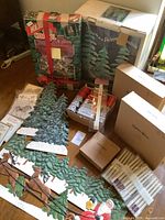 Wide view of lot with mixed boxed and loose holiday decor including green tree stand pieces, boxed carousel ornaments, candles, Santa and reindeer figurines