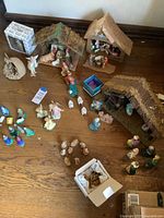 Overview of three nativity stables and multiple figurines including animals and angels on a wooden surface