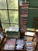 Full view of multiple stacks and boxes of DVDs, showing quantity and condition indoors near window with natural light