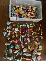 Plastic tote partially filled with various glass ornaments, additional ornaments spread on table