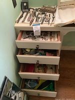 Three-drawer dresser displaying top surface with wristwatches, eyeglass case and eyeglasses; drawers open revealing assorted jewelry and pouches