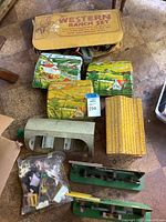 Overview of Marx Western Ranch Set including foldable fabric buildings, gray barn, yellow roof building, and bag of small accessories