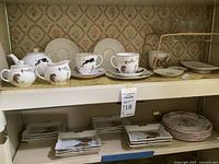 Full shelf view showing cups, saucers, plates, teapot, sugar bowl, and creamer with circus animal motifs