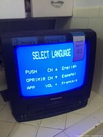Black Panasonic PV-C1340 CRT TV/VCR combo unit turned on, displaying blue screen with 'SELECT LANGUAGE' menu in English, Spanish, and French.