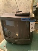 Front view of Sony CRT Trinitron TV with remote control placed on top, showing model and brand labels.