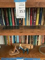 Two shelves filled with vintage books including horror and fiction titles with small woven basket and blue donkey figurine on the lower shelf