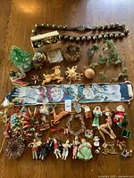 Full lot overview on wooden table showing all items including figurines, garlands, wreaths, textile wall hanging, and various ornaments.