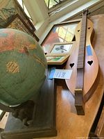 Photo of vintage dulcimer and International Globe with visible heart-shaped sound holes on dulcimer and detailed globe with human figure supports on base