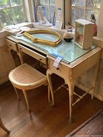 Vintage French Provincial style vanity table with glass top and cane seat bench beside it