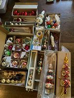 Overview of assorted glass ornaments and tree toppers arranged in original boxes