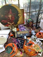 Wide view of lot contents on table by window, showing wall art, lights, figurines, cups, decorations