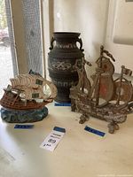 Overall photo showing two ship figurines and the vase together on a white surface with size tags