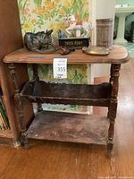 Photo showing vintage wooden side table with assorted decorative items placed on top and two lower shelves; highlights table's overall condition and surface wear