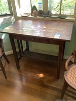 Front view of the wooden writing desk showing the drawer and surface wear.