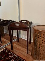 Antique dark wood butler tray on matching folding stand, showing full view against wall and mirror.