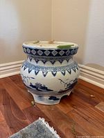 View of the antique Chinese porcelain planter showing blue floral and diamond geometric patterns on a white glazed body, with a wide mouth and three footed legs.