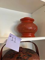 Red lacquered antique Chinese pot placed on a shelf with a note labeled #11.