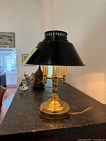 Side view of the antique mini lamp showing the brass base, stem, and black shade.