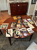 Table top display of cat-themed books, tote bags with toys, and a metal cat bowl photographed from front.