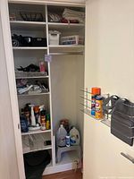Full closet shelving showing cleaning supplies, workout weights, laundry basket, gallon jug and other household items.